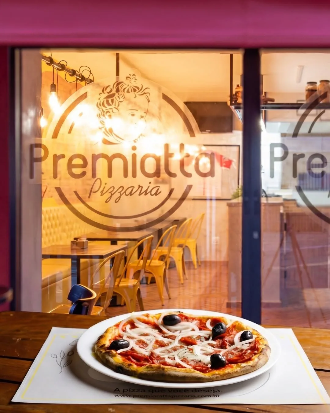 Pizza servida em frente à vitrine com a marca Premiatta